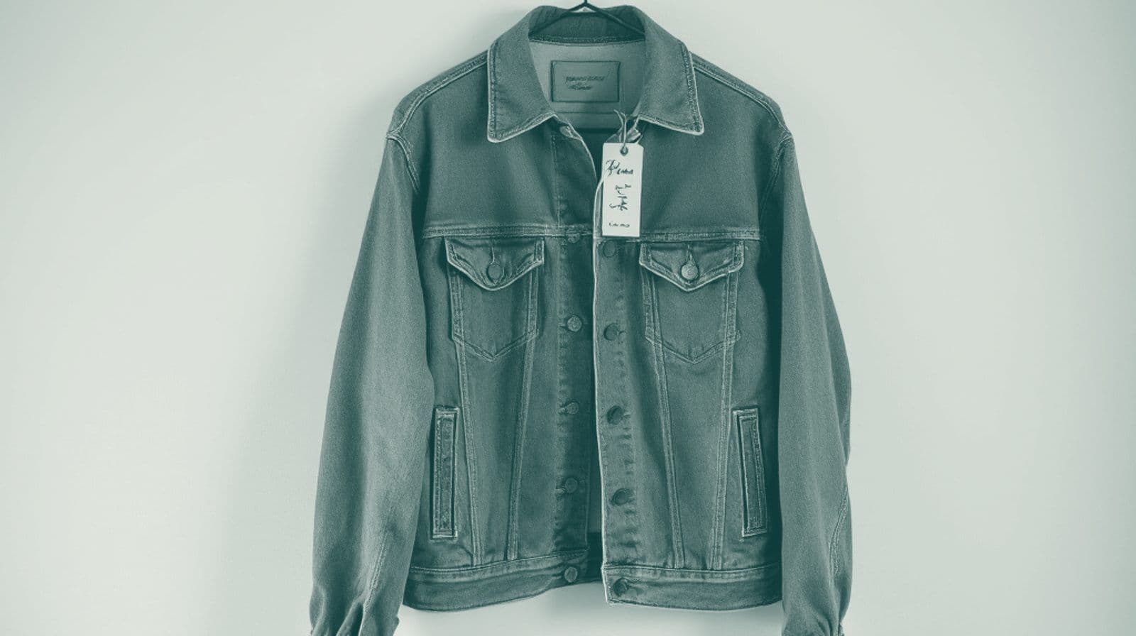 A denim jacket on a hanger with a handwritten price tag attached, displayed against a plain background.