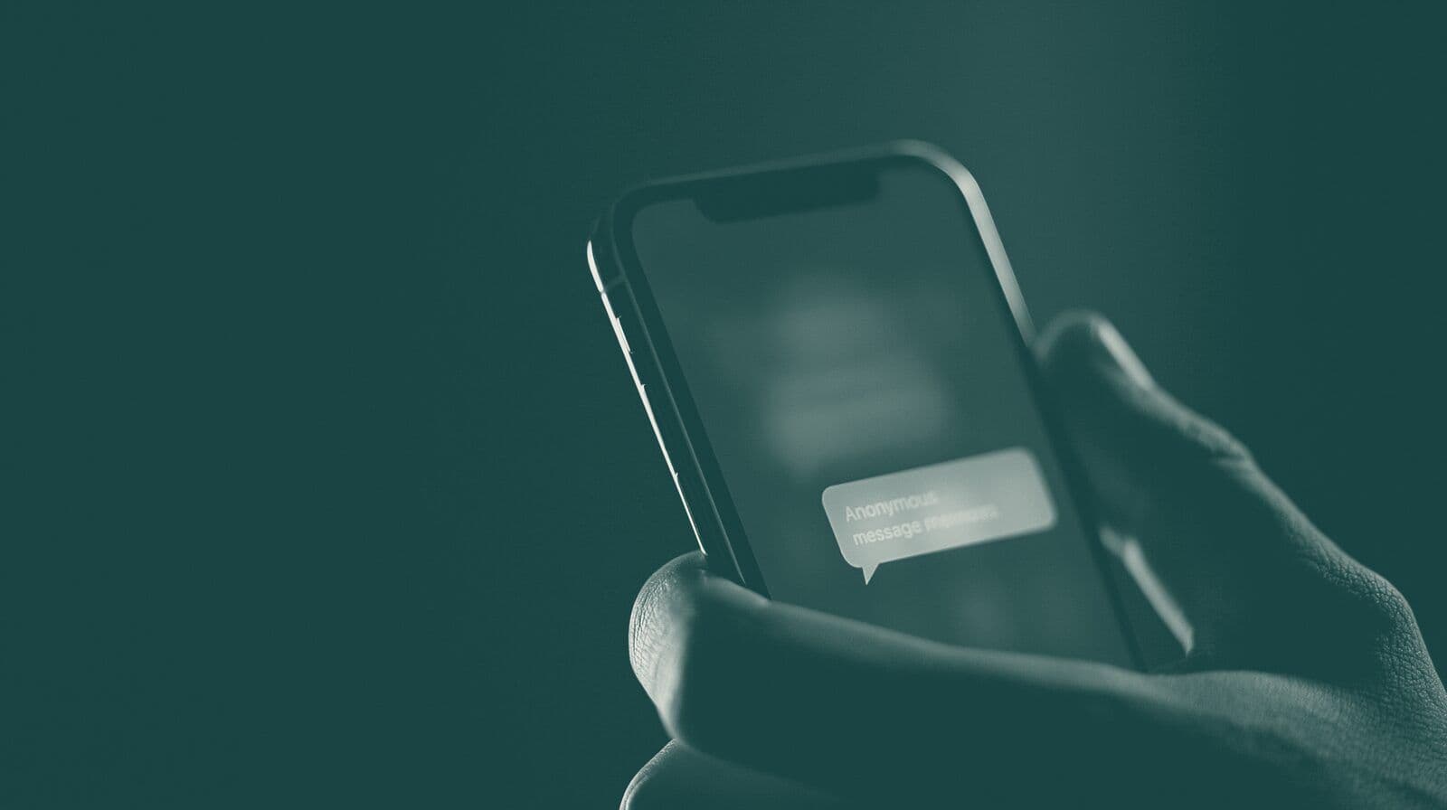 A hand holds a phone in the dark, a message glowing on the screen.