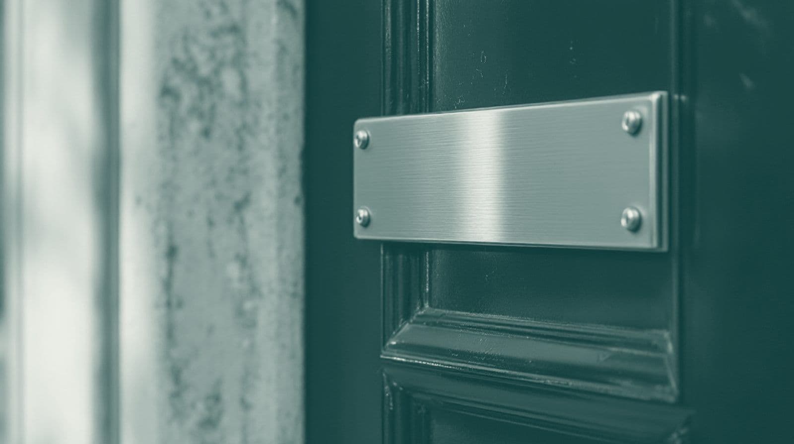Blank metal nameplate on the frame beside a glossy painted door